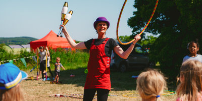 Circus skill workshop performer teaching kids outdoors at Mendip Basecamp.